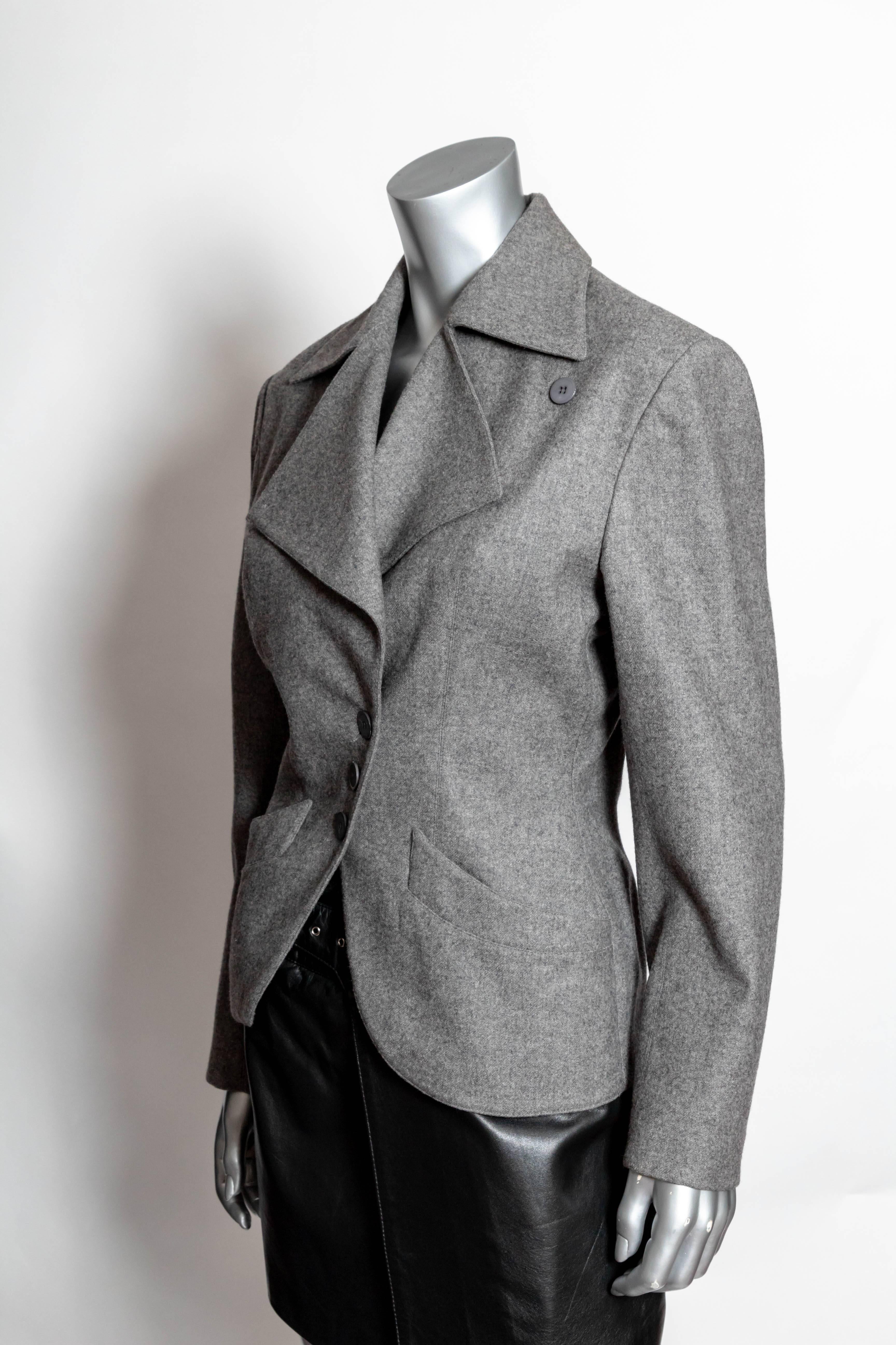 Incredibly chic Azzedine Alaia grey jacket in excellent condition.
Three buttons are positioned asymmetrically with a fourth positioned to close the lapels, giving this jacket an entirely different look. 
Three buttons at each cuff.
Sleeve length
