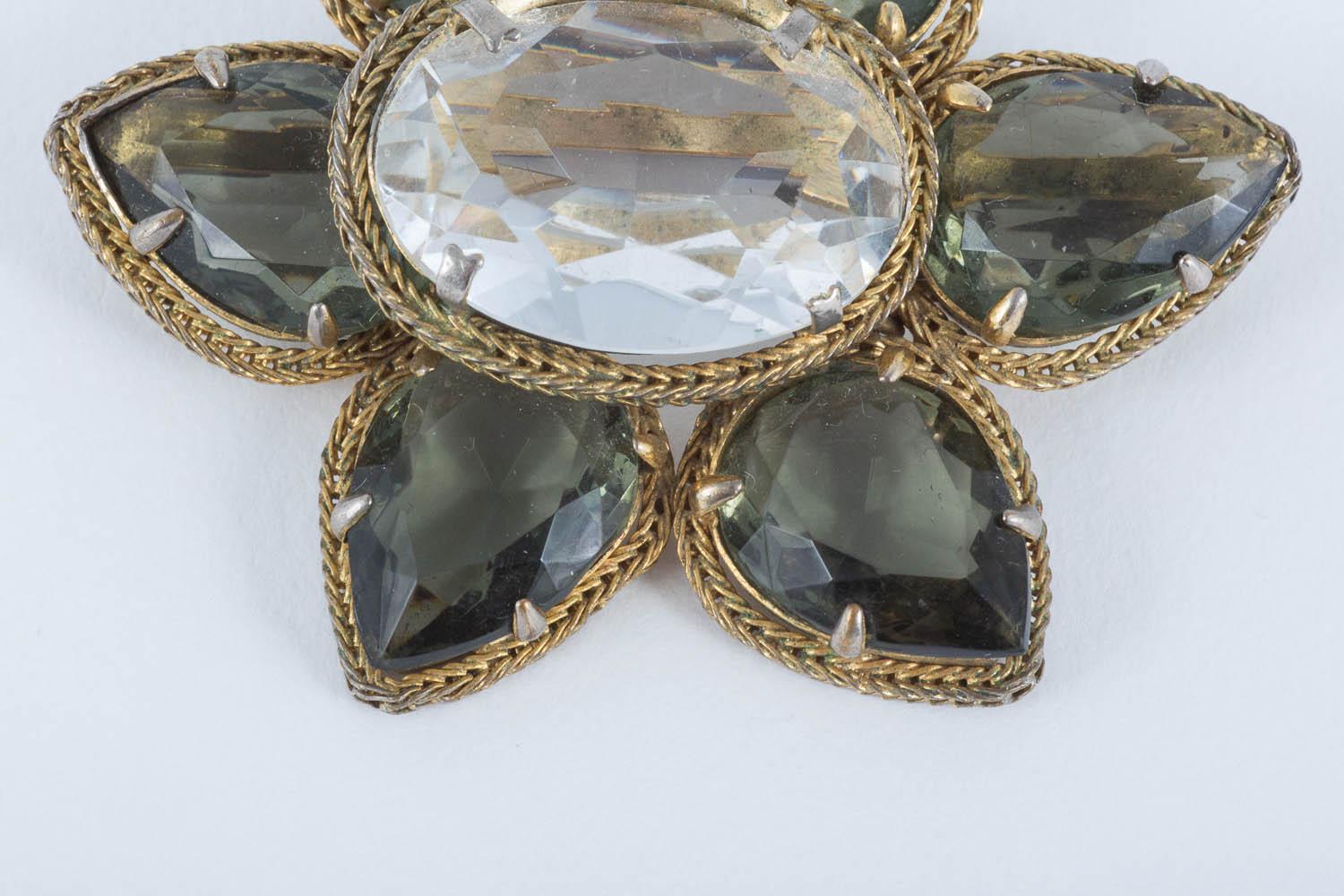 This is a lovely Christian Dior brooch in a very 'grown up' colour combination. The grey petals and large clear oval glass 'stones' sit so well with the lovely antique gilded metal surround. The brooch is signed and dated.
A great addition to any