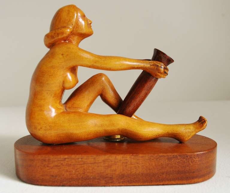 A charmingly carved seated female nude in blonde wood sits on a walnut stained base and clasps a walnut pen quiver with a brass mount to the base.