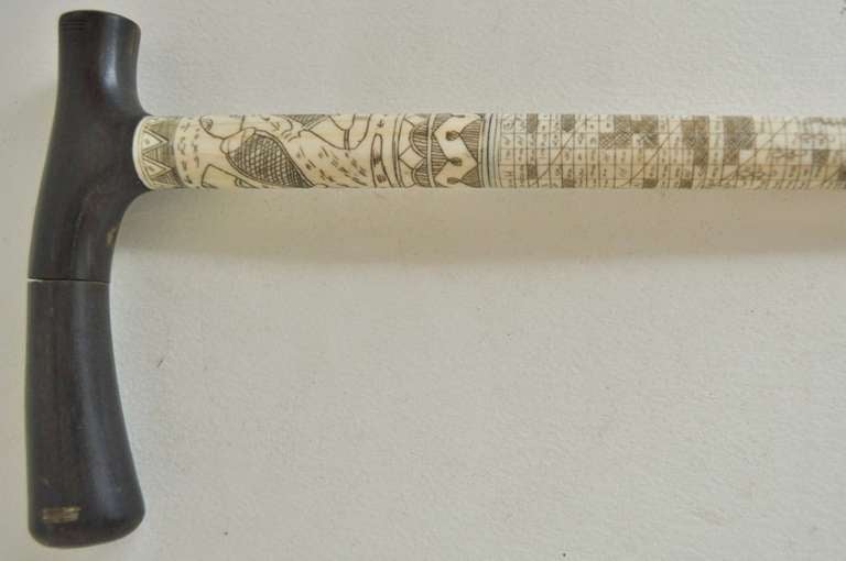 Batak walking cane or stick with incised bone shaft with L-shaped horn handle and horn ferrule. The bone shaft has an inside foundation consisting of a metal rod. The skeletal shaft itself is incised and stained with divinitory calendars plus