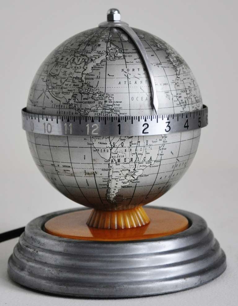 This extremely rare American Art Deco lithographed tin and butterscotch Bakelite world clock is signed in about 6 point type just above the Antarctic by the celebrated American cartographer, Kermit Bishop. The globe itself is printed in shades of