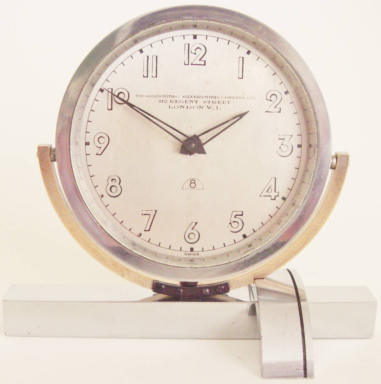 This high-end English Art Deco asymmetrical chrome and brass 8-day mechanical shelf clock has a 15 jewel Swiss movement and on the face bears the London mark of The Goldsmiths and Silversmiths Company Ltd. of 112 Regent Street. The design is
