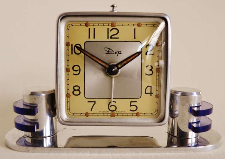 This beautiful small chrome-plated mechanical alarm clock is accented on either side with semi-circular discs of transparent blue Lucite. It bears the trademark of the French manufacturer 'Dep', producers of some of the best Art Deco designed clocks