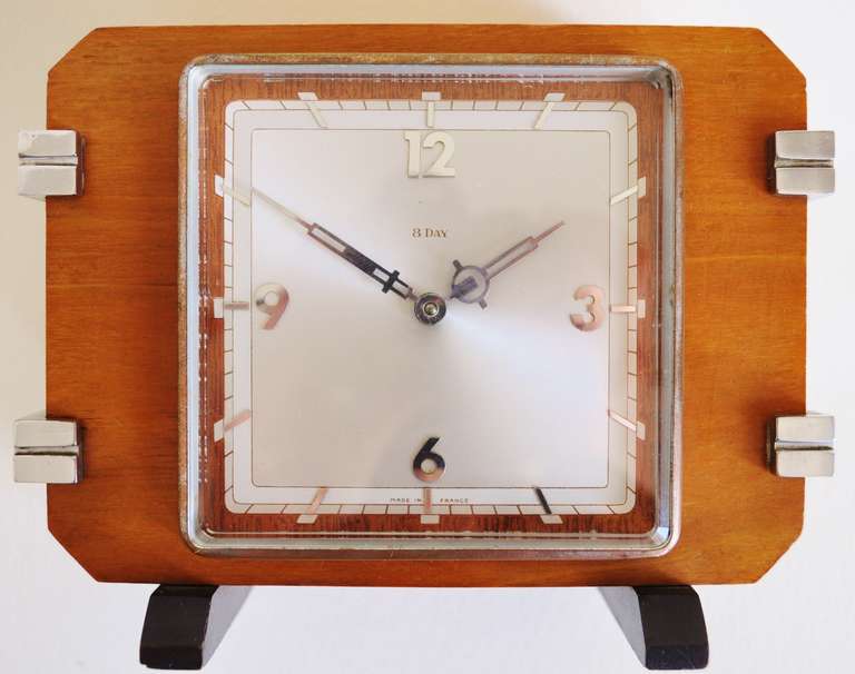 This beautifully designed French mechanical 8-day shelf clock features a Lever movement housed in a solid blonde walnut cabinet. It stands on feet of ebonised wood and is banded by geometric chrome accents. It is in excellent condition overall with