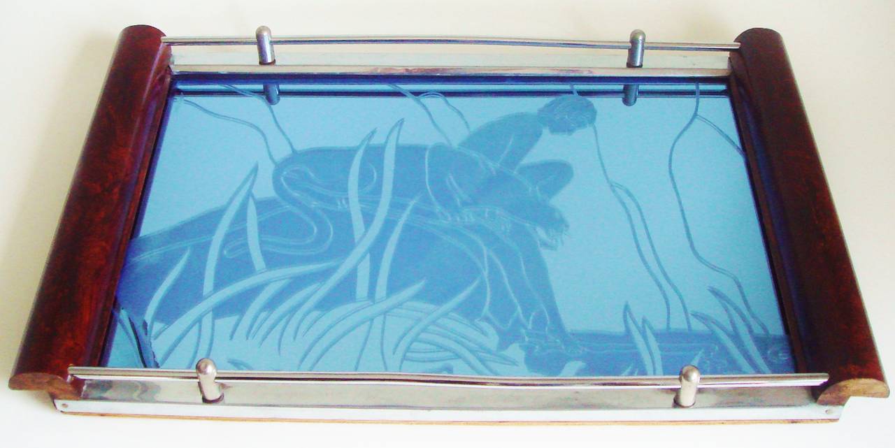 This stunning and very rare American Art Deco cocktail tray has a chrome frame and gallery rail with faux grained wooden handles at each end and four rubber bun feet to the underside. The reverse etched cobalt blue mirror depicts  a young boy