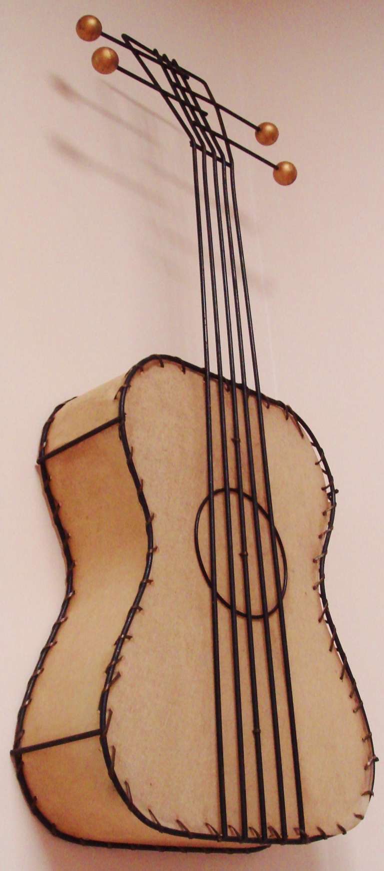 This Iconic American Mid-Century Modern figural guitar wall lamp by Frederick Weinberg is one of a series of 5-stringed instrument lamps that he created for his interior accents company, The Frederick Weinberg Company of Philadelphia. This example