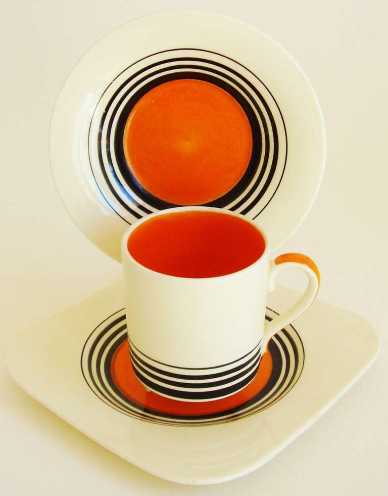 This fabulous set of four coffee can trios (each with coffee can, round saucer, square cake plate) are examples of the Tango pattern which was designed in various color ways by Susie Cooper in 1934. Of all the variations, the orange, black and cream