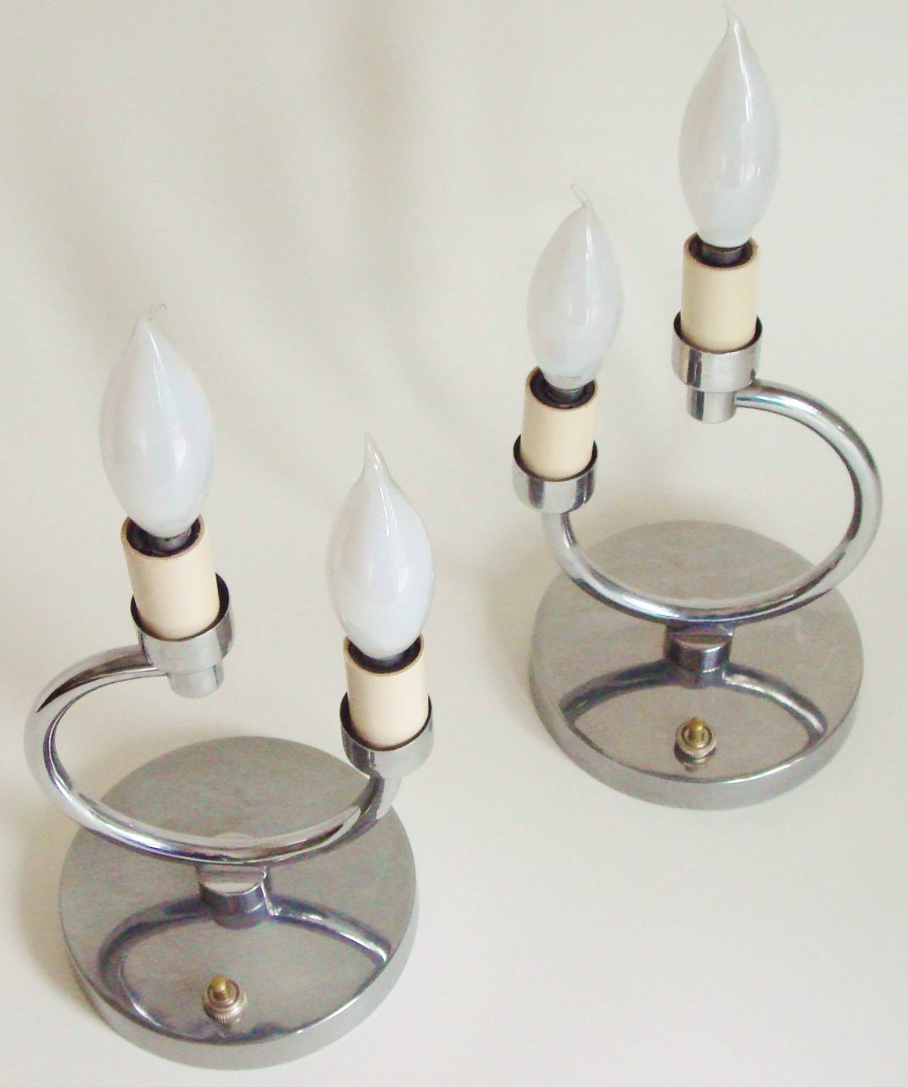 This charming and unusual pair of French Art Deco chrome geometric twin faux candle boudoir lamps each feature a bold 