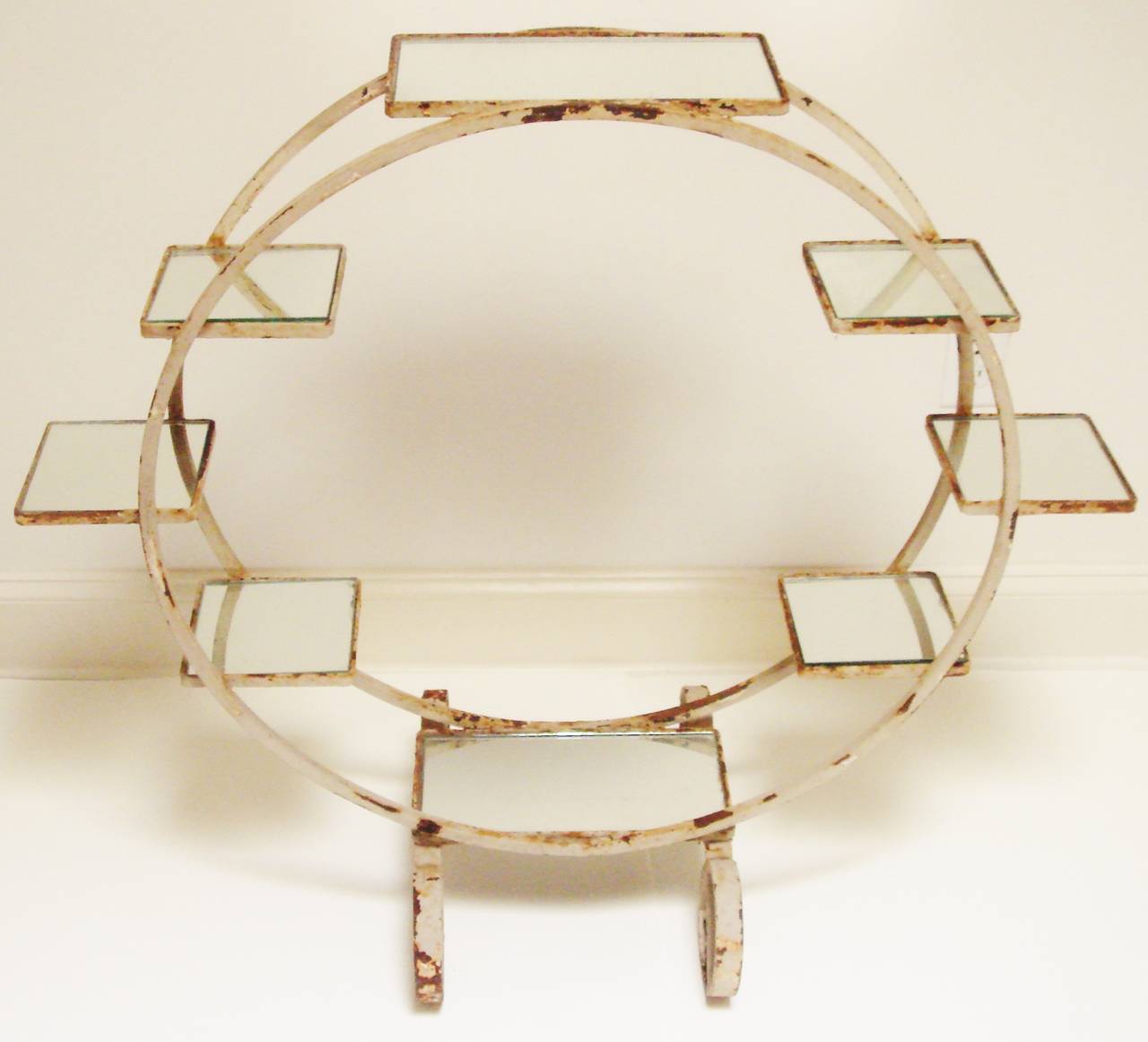 This stunning American Art Deco painted circular iron garden or conservatory plant etagere is designed like a stationary carousel. It has six mirror lined square shelves that range around the circumference of the double circles plus two double sized