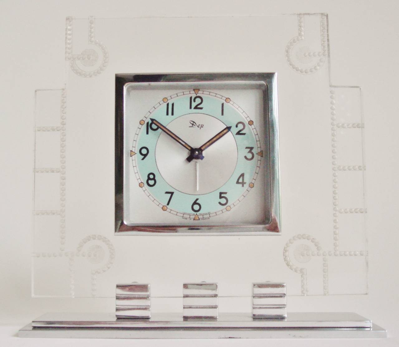 This rare and extremely pretty French Art Deco alarm clock features polished aluminium and chrome accents framed by a clear Lucite body. This clear Lucite panel is reverse dot etched in a geometric pattern. The face itself carries the script logo of