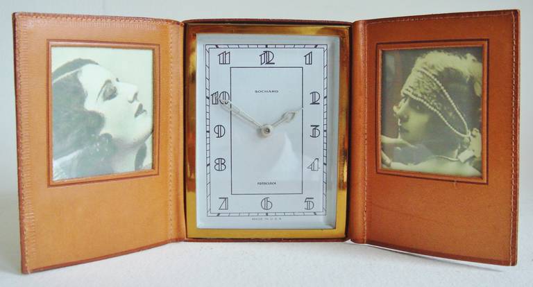This near mint American Art Deco leather bound combined travel clock with  photo-frames was patented (Des.Pat.No121123) in 1940 by Brooklyn's Henry Sochard. When folded-up for travelling it is a compact 3