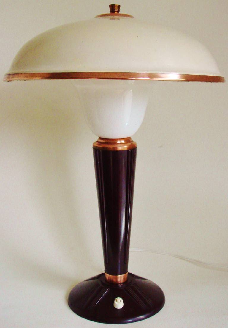 This iconic pair of late Art Deco French 'Luxury 320' table lamps by Jumo feature brown and burgundy Bakelite bases, original ecru enameled metal shades with copper accents and finial plus white Lucite reflectors. While their design inspiration is