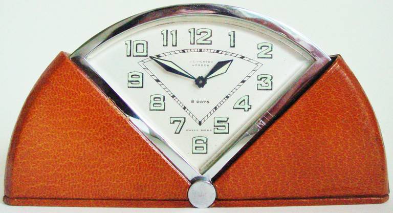 This rare Swiss Art Deco Travel Clock was manufactured for the English market and is auto-wound by opening and shutting the case. The mechanism is housed in a chrome plated brass case with a tan leather covering. Both only show very light evidence