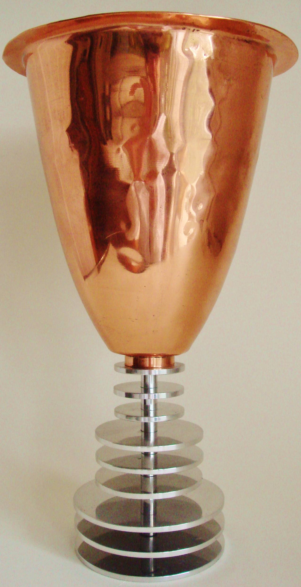 Produced in limited numbers during the late 1980s, English designer, Keith Gibbons crafted this stunning and distinctive vase. The vase along with a companion bowl and dish  each used the contrast of the spun copper with the tiered aluminium disc