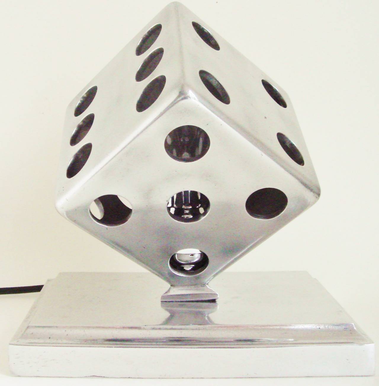 This American Art Deco or Machine Age buffed aluminium accent lamp is in the form of a dice with one removable side panel to facilitate the changing of the bulb. The piece has been re-wired with a black flex and in line switch and the interior