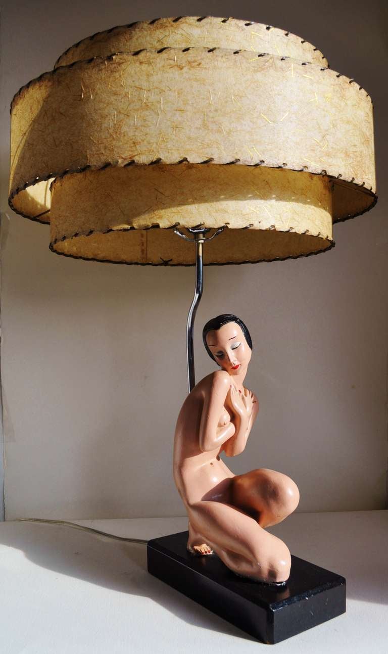 This large table lamp features a beautiful Alexander Backer polychrome plaster figurine of a kneeling female Asian nude demurely covering herself is mounted on a black enamelled wooden base. The chrome light fitting is topped with its original