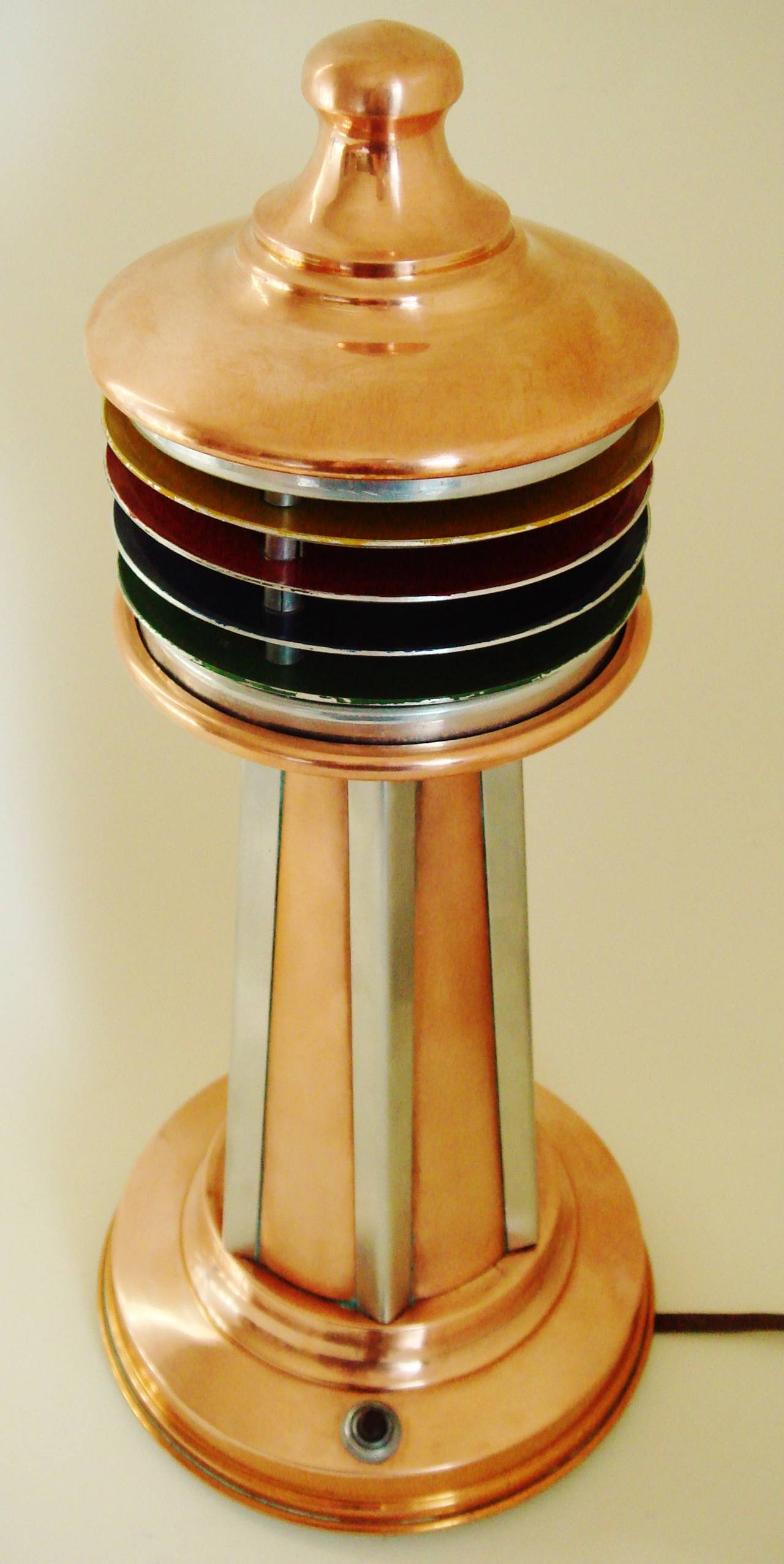 This great American Art Deco or Machine Age anodised aluminium table lamp is constructed as a sort of Buck Rogers spin on a conventional lighthouse. The louvred rings that comprise the shade have been anodised in a rainbow of colours and give a