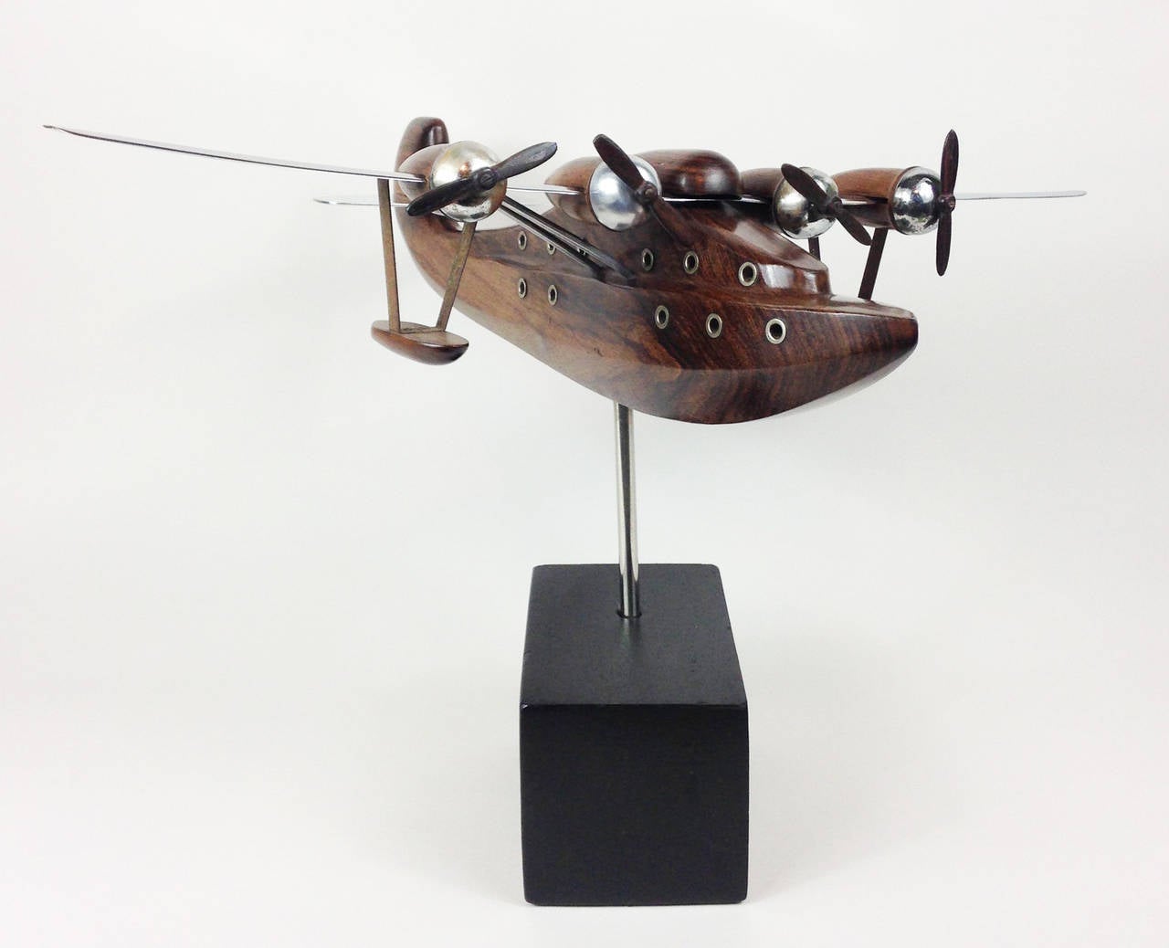 A wonderful desktop model of a flying boat or seaplane. 

Constructed of beautifully carved Indian rosewood with chromed aluminium wings, tail section and engine cowls. Further aluminium details support the underside of the wings, the floats and