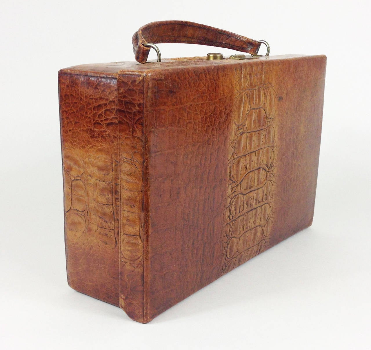 A wonderful simulated crocodile skin leather case of extremely small proportions.

The leather is in beautiful condition, whilst the edges, seams and handle are strong and on the whole damage and wear free. The brass lock still functions well