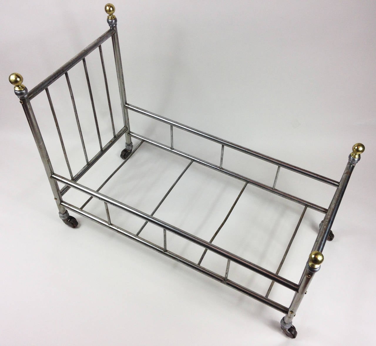 A very well made antique metal bed frame with brass bed knobs and metal casters.

Due to the unusually large size of this piece, it has a variety of uses apart from the purely decorative. It can used as a book, magazine, rack and even a small dog