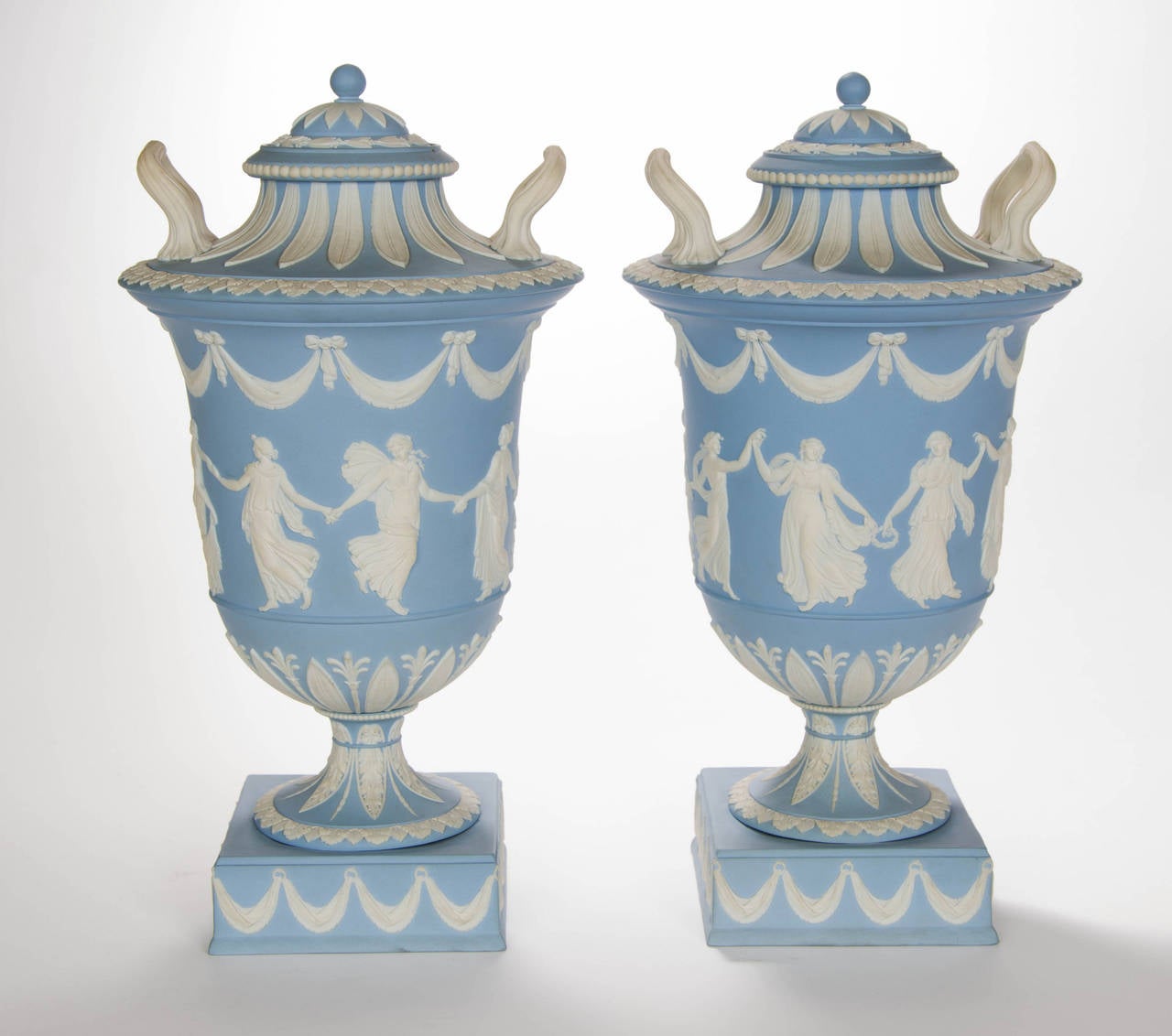 A splendid Pair of Wedgwood jasper ware Vases decorated with classical figures, Dancing Hours with swags above on pedestal base