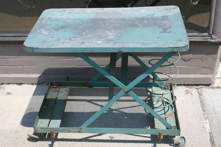 Adjustable height Industrial scissor table on wheels with a spring! The table as pictured is as high as it can go. Great green paint, nicely weathered from use over steel.