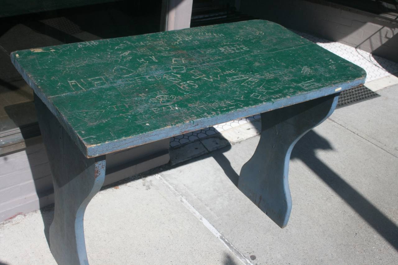 Great completely covered Graffiti table, circa 1940s. Lots of carved nicknames, a monkey's face, lovers, the date 1947 and many interesting sayings. A nice slice of history that is also a table. Green painted top is original with blue base. May have