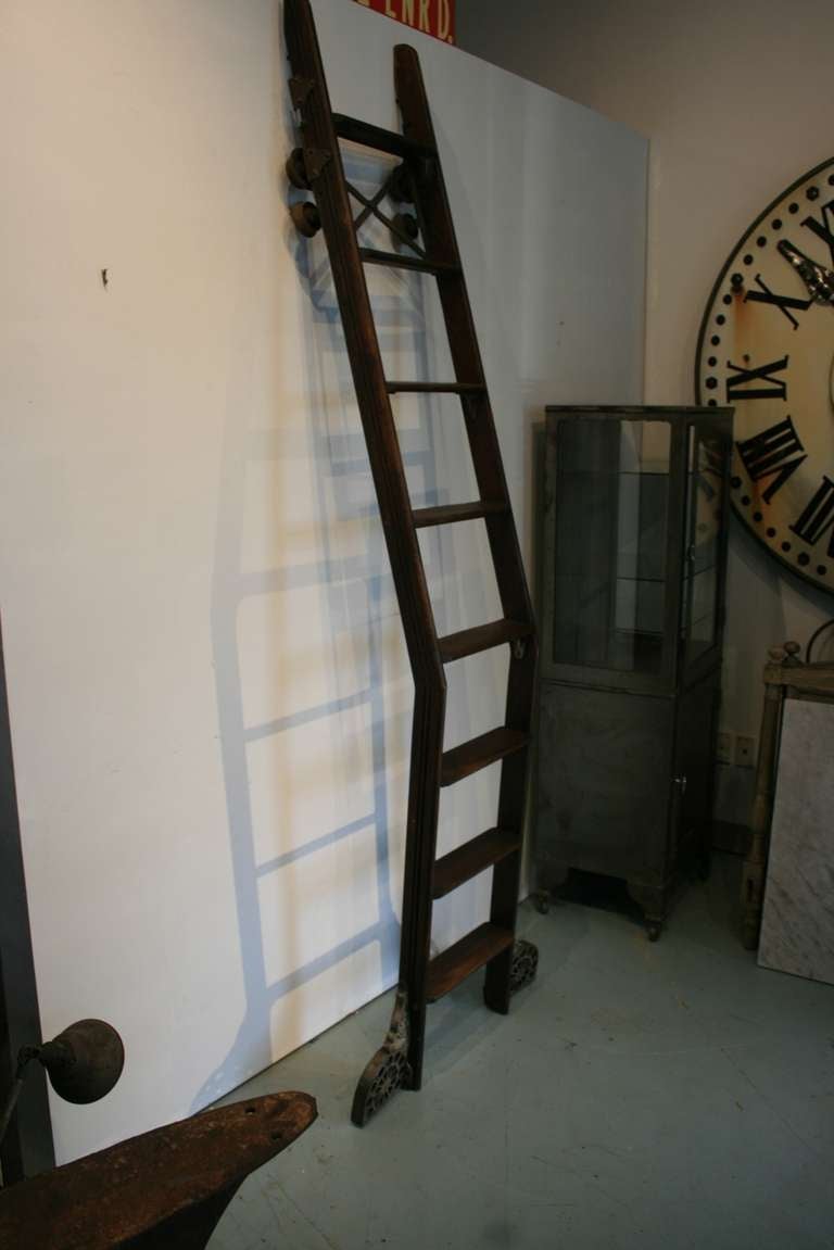 Exceptional 19th Century Library Ladder.  The metal work covering the wheels makes the piece.  The dark wood, the way it cants out from the wall, and the track wheels on top all make    a great sculptural  statement. Came from a store in Providence