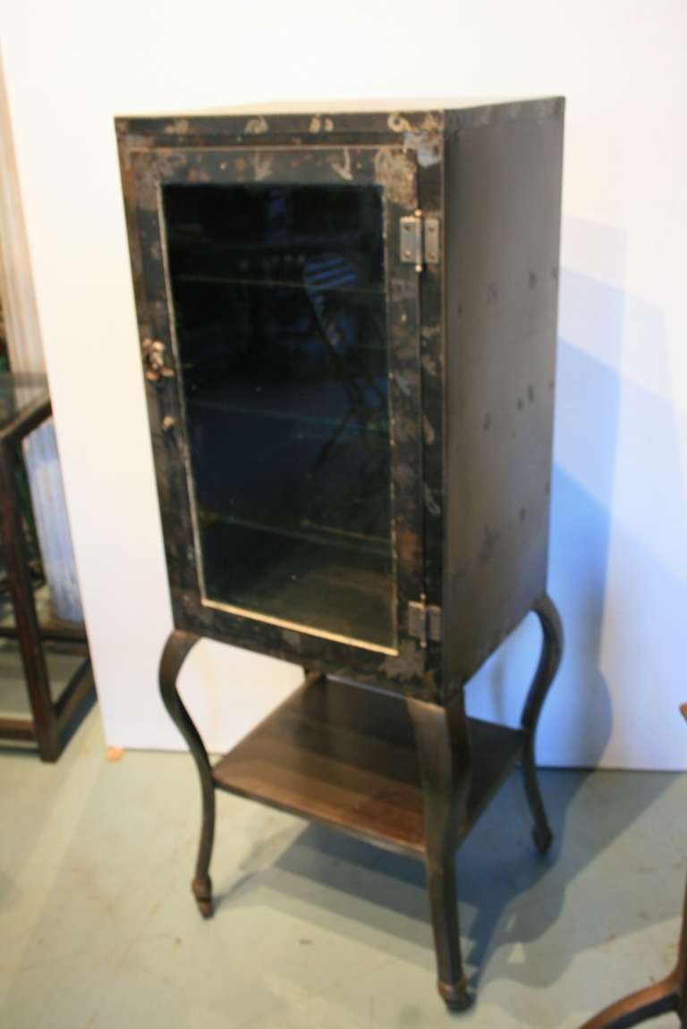 Early doctor's or medical cabinet. Great sculptural look. The cabinet has cabriole legs, wheels, and three 3/8 inch thick glass shelves. All original.