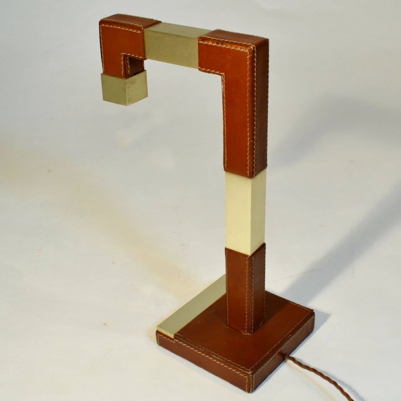Rectangular table lamp in stitched mid brown hide leather and brushed brass.