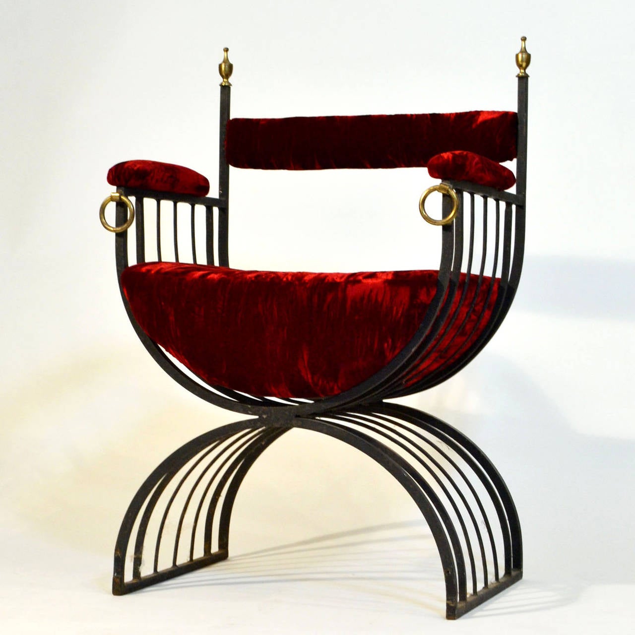 Forged metal chair with brass details re upholstered in ruby crushed velvet.