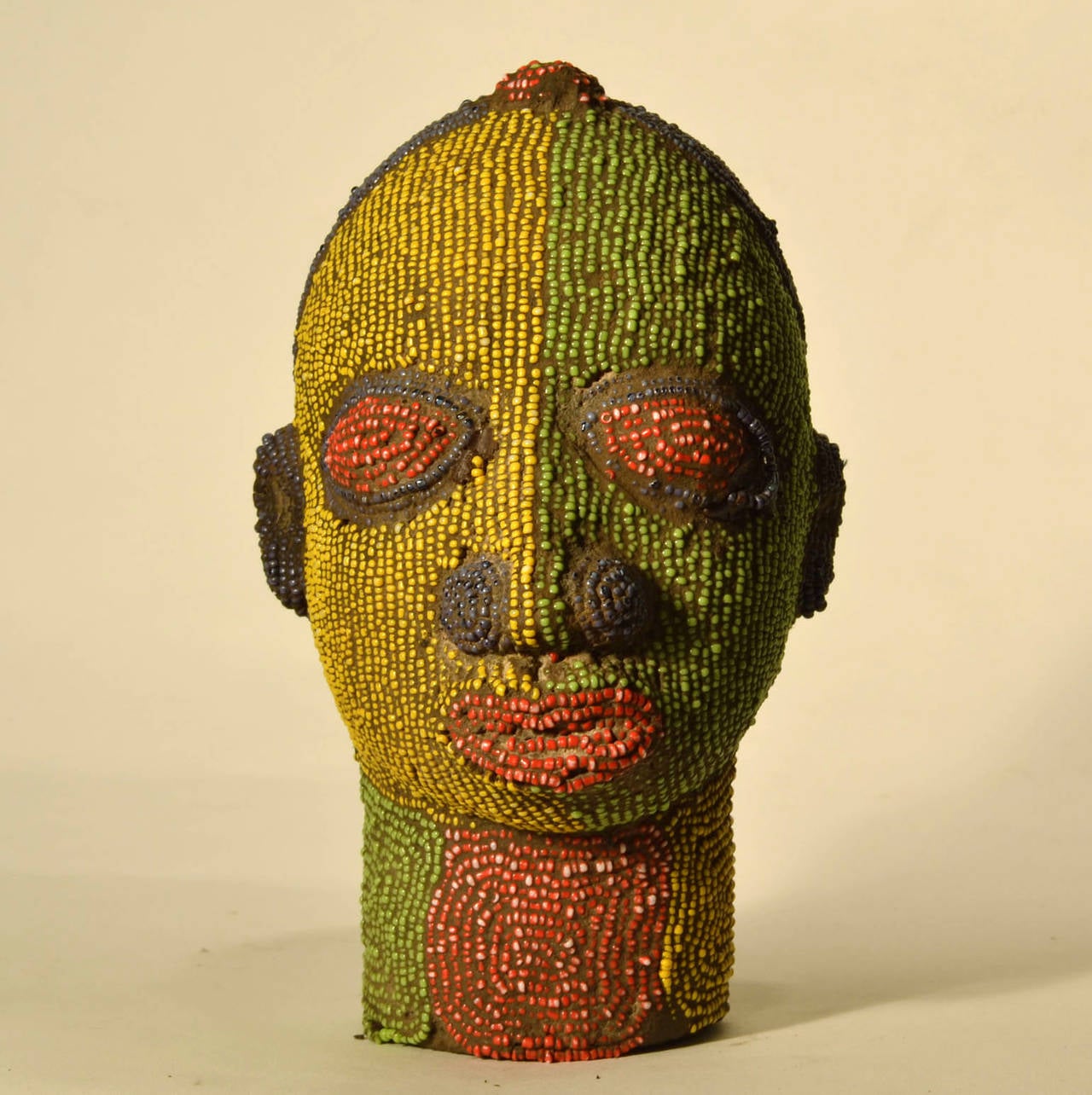 Brightly coloured beaded terracotta head commissioned in the 1960's to decorate wealthy Nigerian homes. The terracotta sculpture is inlaid with strings of beads over its ceramic form.
They sometimes came in pairs as man and women or two females.