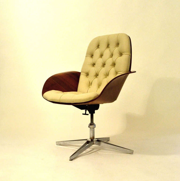 An organically-formed plywood seat in rosewood, upholstered in creme leather that sits on a chrome four-point tilted star-shaped leg. The height is adjustable and the chair can be angled for comfort.