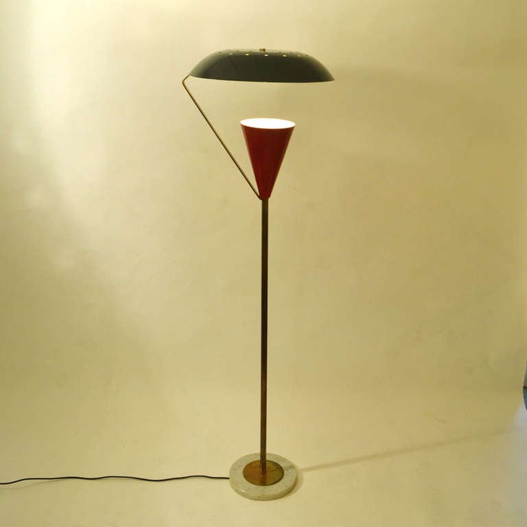 This monumental floor lamp consists of a cone shaped lamp holder and a saucer shaped light reflector perforated in a sun ray pattern.
The two pieced shade is enameled black and red with a brass arm connecting the two pieced shade to the stem.
The