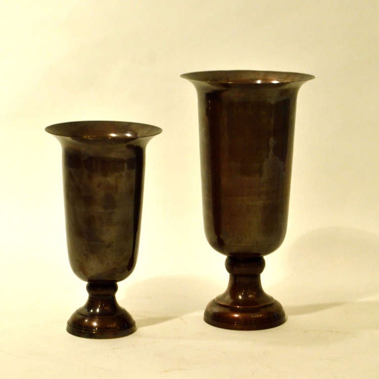 Two large brass vessels in different heights, patinated in a bronze tone.
Dimensions largest vessel:
Height 42 cm
Width 23 cm

Dimensions medium vessel:
Height 34 cm
Width 19 cm