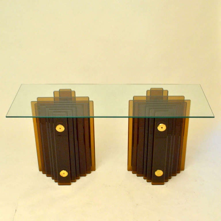 Expressive pair hand beveled amber glass pedestals are a base for a large clear glass dining table, desk or console.
They are constructed from nine 15 mm thick rectangular shaped glass plates layered behind each other and separated by brass spacers