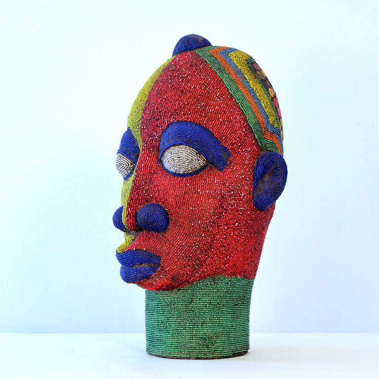 Brightly colored beaded terracotta head commissioned in the 1960s to decorate wealthy Nigerian homes. The terracotta sculpture is inlaid with strings of beads over its ceramic form.
The artist was influenced by 16th century Benin bronzes.