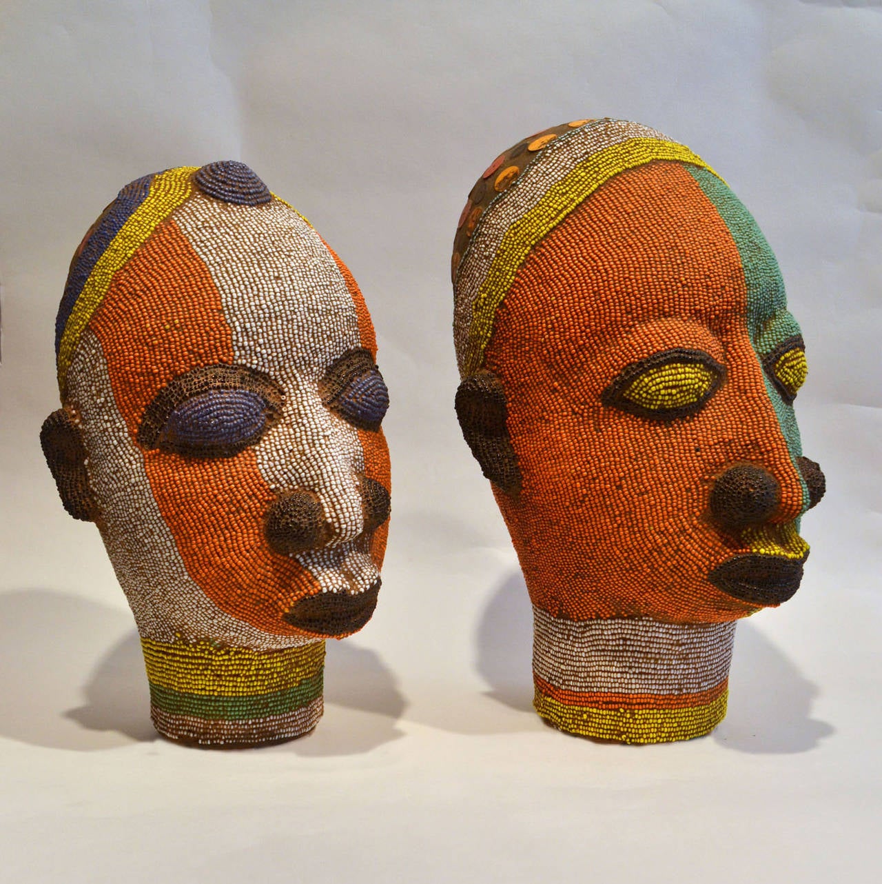 Brightly coloured beaded terracotta head commissioned in the 1960's to decorate wealthy Nigerian homes. 
The terracotta sculpture is inlaid with strings of beads over its ceramic form.
The artist was influenced by 16th century Benin bronzes.