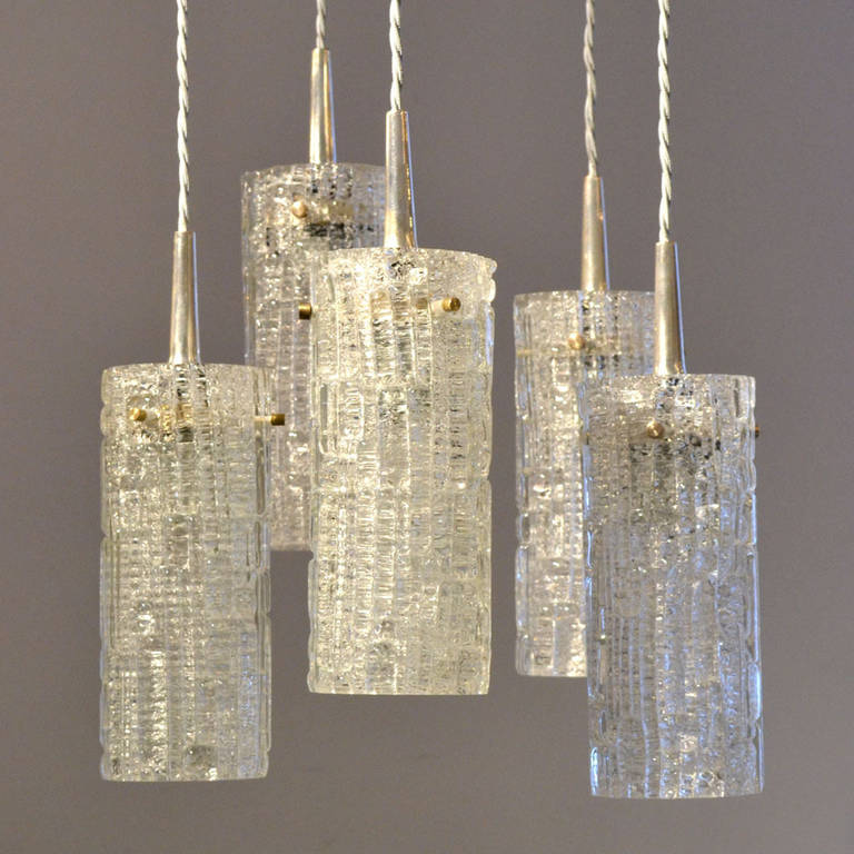 Five clear glass relief glass cones are connected by nickel plated arm fixings. The heights of the cords can all be adjusted. They can be hung in a circle with alternating heights or over a table or kitchen isle in a row
The individual lights