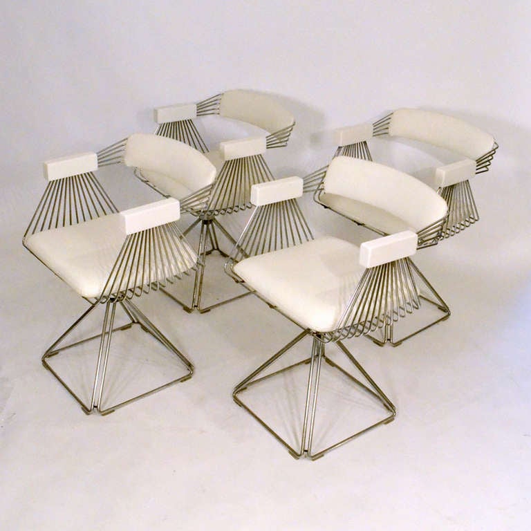 Wire frame chrome dining chairs on a swivel base re-upholstered with white leather. Two of the chairs have a tulip shape foot and the other four bases are pyramid shaped.
Designed by Tony Verhulst for Novalux,
