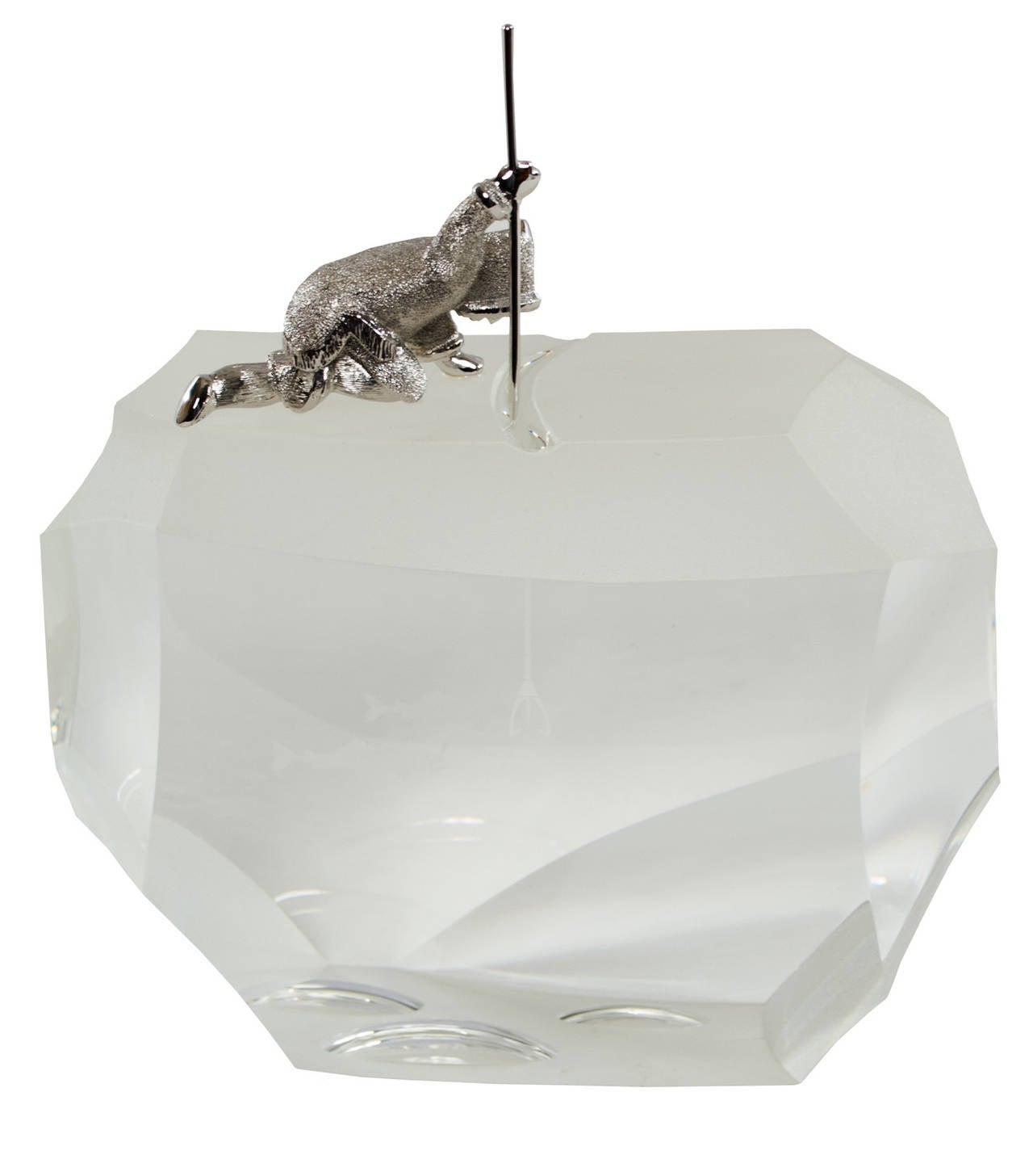 A solid crystal sculpture with a sterling silver Eskimo ice fishing with a spear designed by the artist James Huston for Steuben glass.