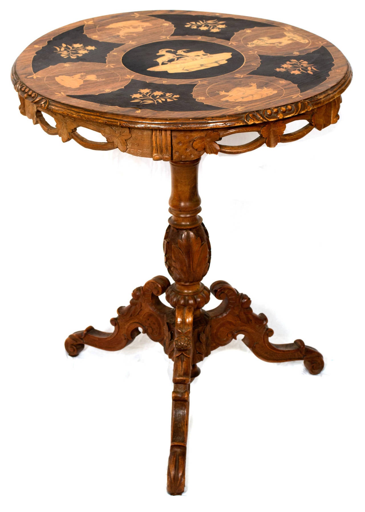 A late 19th century circular occasional table made in Switzerland; the top featuring five beautiful marquetry panels of chamois and other animal groupings and interposed with floral sprays in exotic, fruit and ebonized woods. The skirt of the table