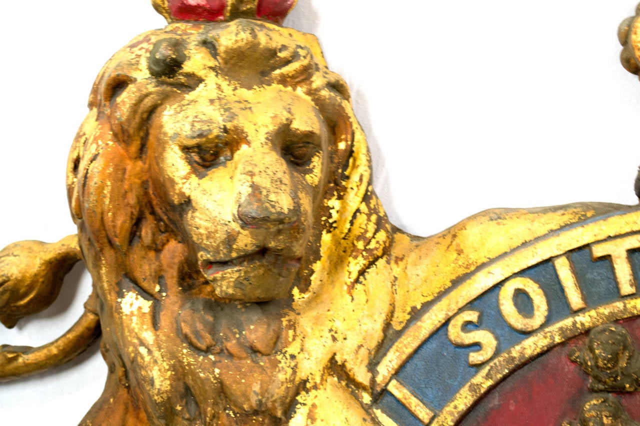 A monumental polychromed iron crest of the British Royal Crest, including the Lion of England and the Unicorn of Scotland with the words above (