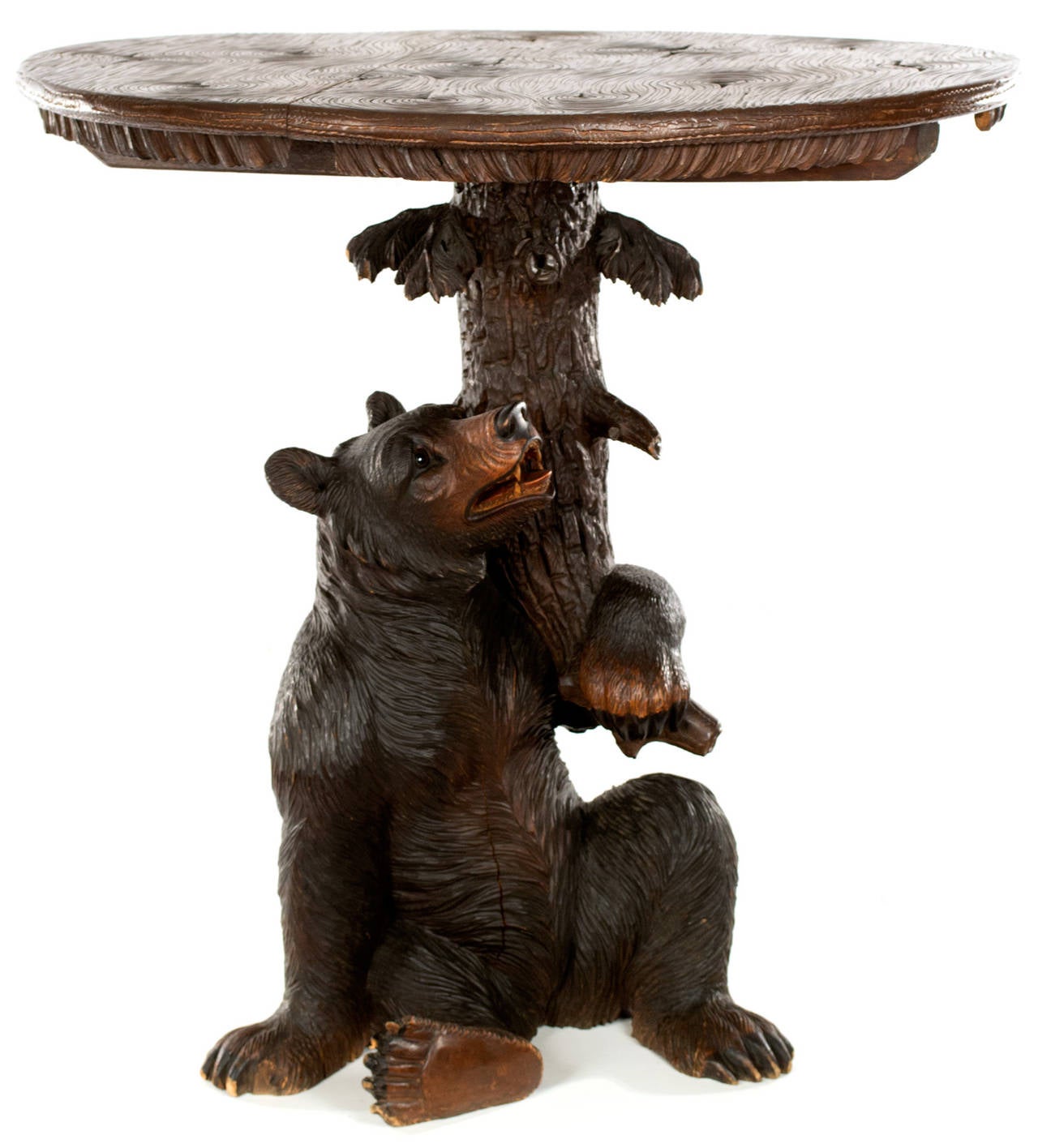 Featuring a large carved and polychromed black bear with glass eyes made up the central column of the table and appears to be holding up the top, which is elaborately carved with deep grooves to mimic the appearance of grained wood. This virtuosic