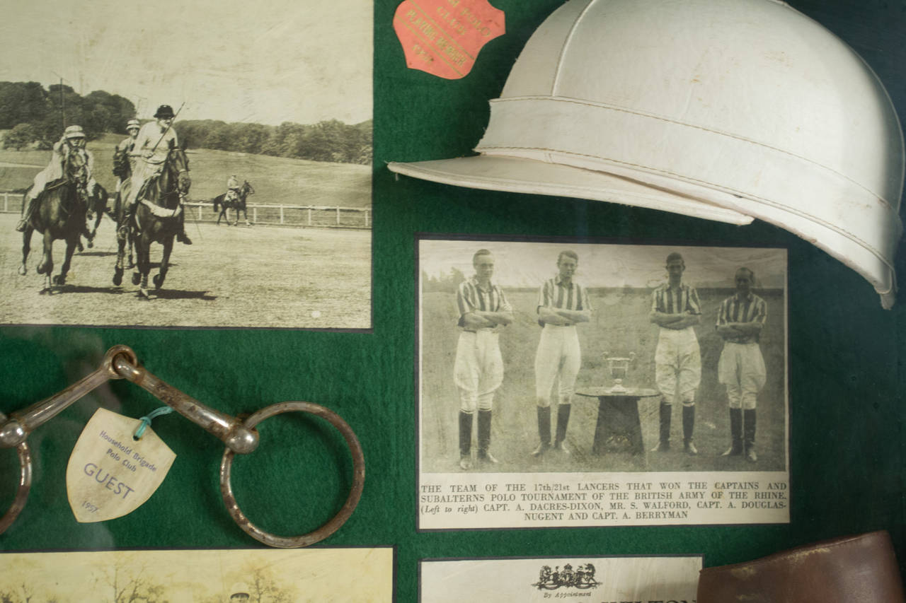 A shadow box, backed with green felt festooned with photos of early-nineteenth-century polo teams, a polo trophy, hammer, helmet, and leather boot.