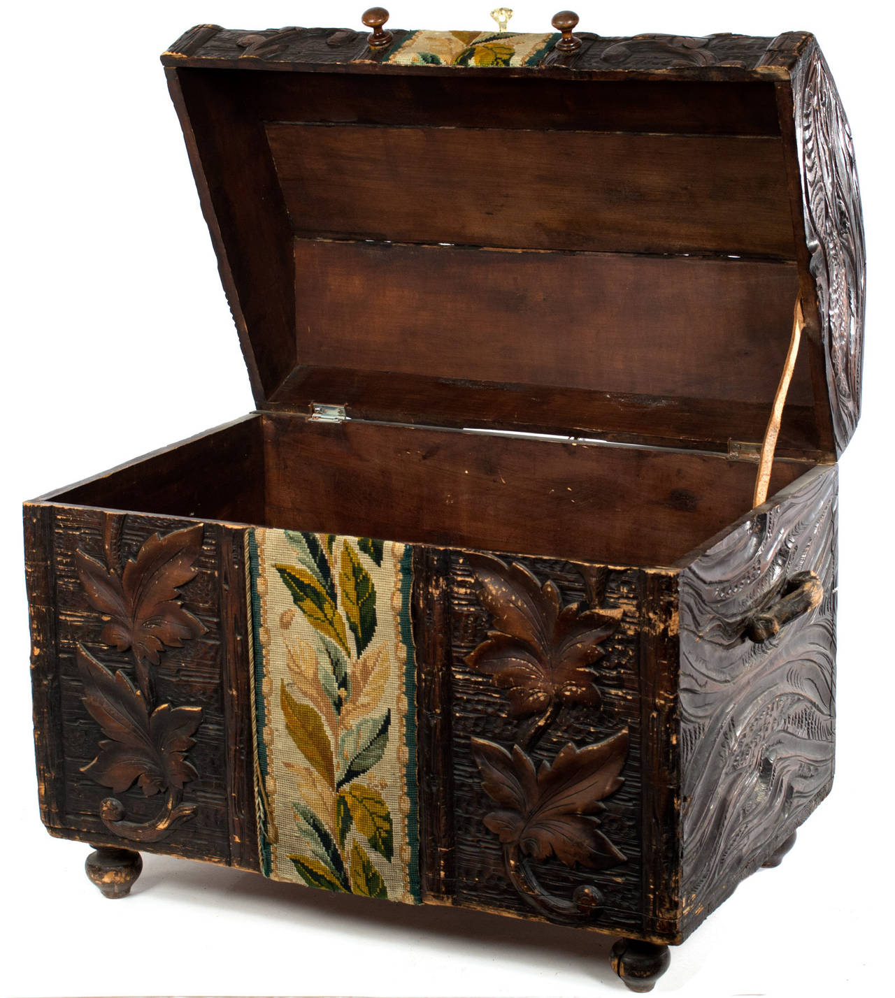 Elaborately carved with patterns of leaves, vines, grooves, and bark this Hungarian  chest has a gros-point needlework tapestry runner along its top and front. With original leather handles, this work is remarkable both for its artistry and for
