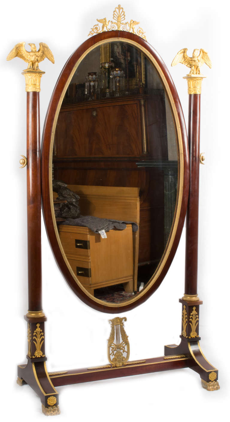 This large mahogany and ormolu mirror and stand dates bears witness to the French rival of Greco-Roman classicism (e.g. eagles, acroteria, honeysuckles, corinthian columns) and the re-discovery of Egypt (i.e. the pair of sphinxes surmounting the
