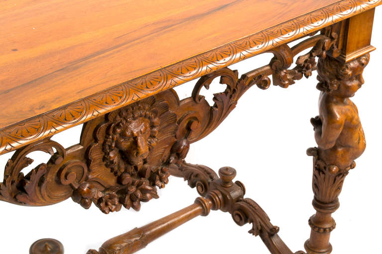An elaborately carved Italian walnut table featuring pierced strapwork skirts with lion masks, four legs — each with putti atlases holding up the table and acanthus leaves —  the base is made of solid scrolls elaborately carved with foliage.