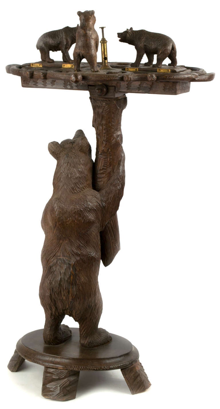 With a a brass cutter and compartments for the storage of cigars and their cuttings, this stand is made of  three exquisitely carved, polychromed bears in linden wood.