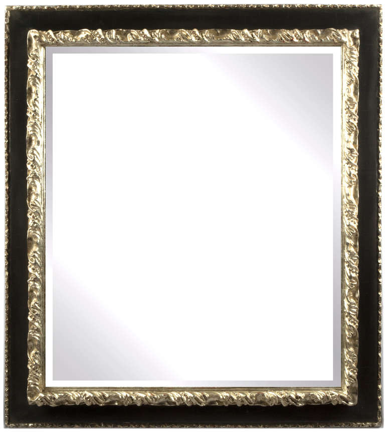 A large Baroque style mirror with bevelled glass and a frame that has been silvered along its inner and outer frame. The silver is actually 12 carat gold, which, has the appearance of silver, but will not tarnish.